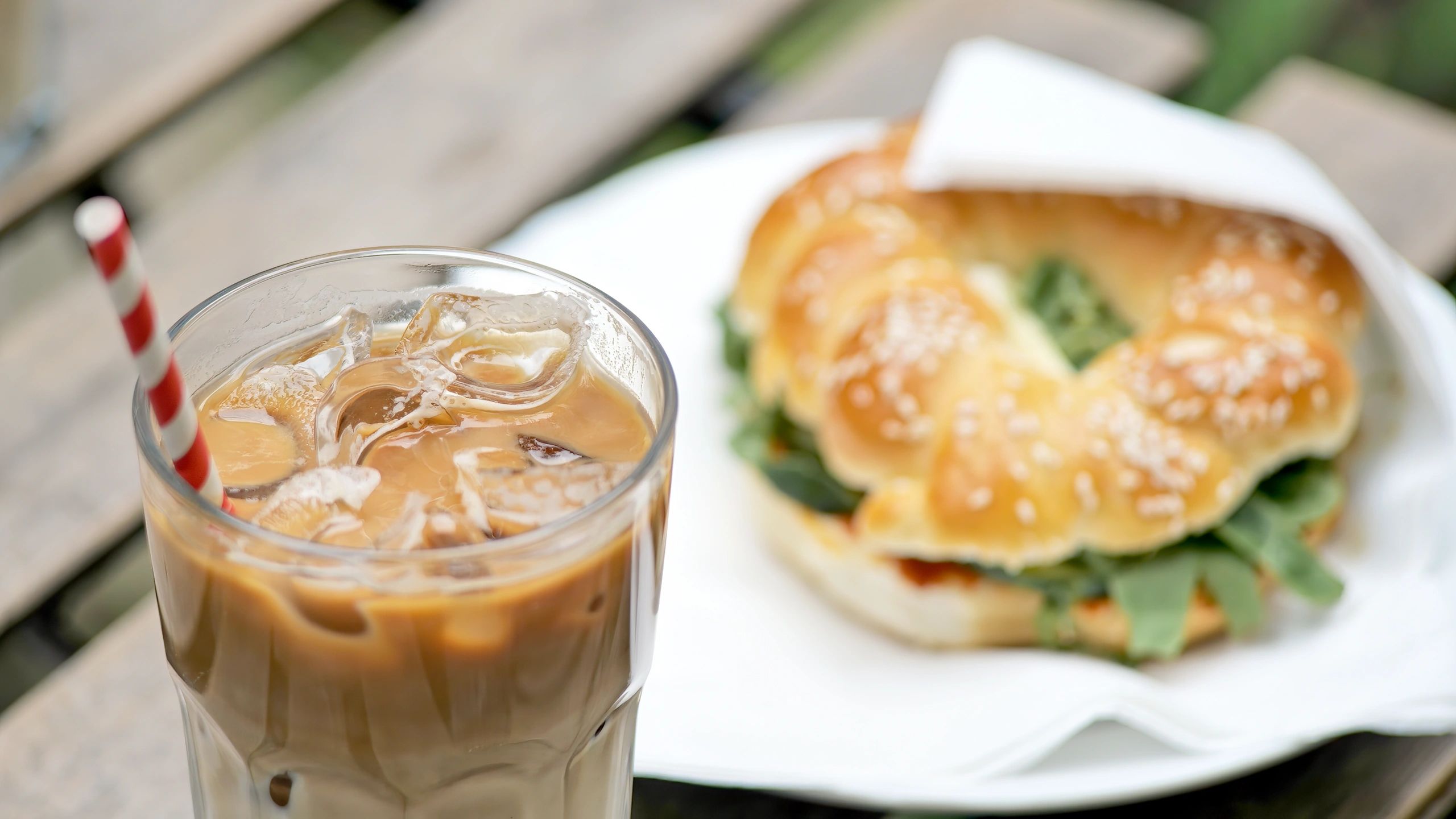 Breakfast plate with iced coffee and sandwich at a cafe table